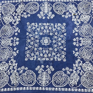 May include: A square, navy blue bandana with a white floral and leaf pattern. The design includes a central floral motif and a border of stylized leaves and flowers. The lower right corner has the text "FAST COLOR COTTON".