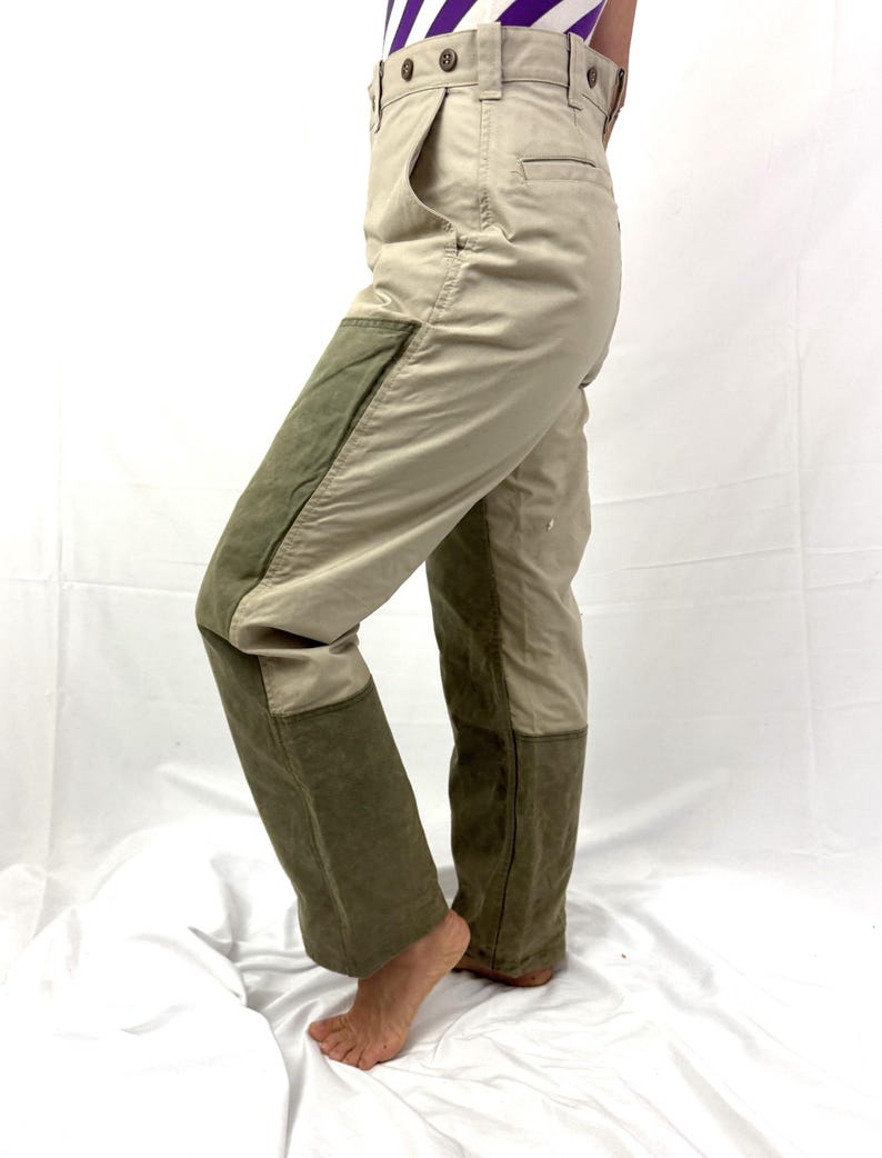 Puede incluir: Pantal&oacute;n de trabajo beige y verde con un parche en la rodilla y un bolsillo lateral. El pantal&oacute;n tiene cierre de bot&oacute;n y trabillas para el cintur&oacute;n.