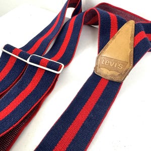 Op de afbeelding: Blauw en rood gestreepte bretels met een leren Levi's patch. De bretels hebben een klassiek ontwerp met een witte metalen sluiting. De stof is een geweven materiaal.