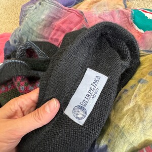 May include: Black alpaca sweater with a white label that reads "ESTIRPE INCA Alpaca".