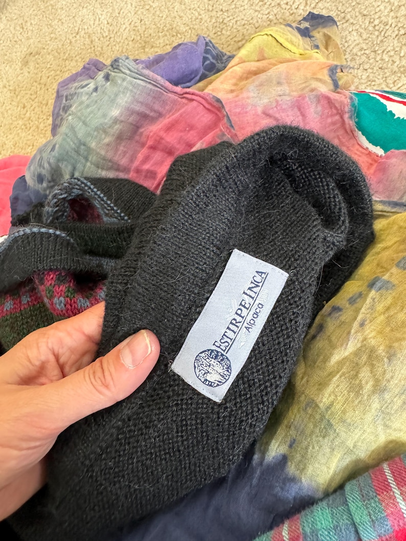 May include: Black alpaca sweater with a white label that reads "ESTIRPE INCA Alpaca".