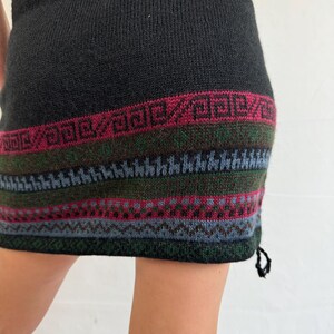 May include: Black knitted skirt with a colorful geometric pattern at the hem. The skirt is made of a soft, warm material and has a drawstring at the side.