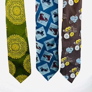 May include: Three neckties with different patterns. The first tie is green with a gold geometric pattern. The second tie is blue with a white and red car pattern. The third tie is brown with a white and yellow floral pattern.