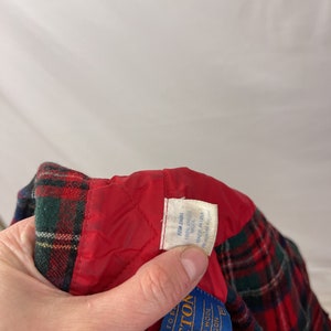 May include: Red and green plaid flannel shirt with a red quilted lining. The shirt has a blue label that reads "Pendleton" and "100% Pure Virgin Wool" with the text "Portland, Oregon" and "Since 1883".