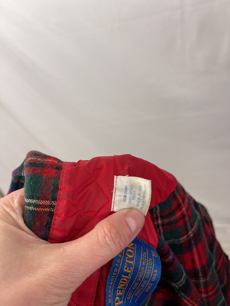 May include: Red and green plaid flannel shirt with a red quilted lining. The shirt has a blue label that reads "Pendleton" and "100% Pure Virgin Wool" with the text "Portland, Oregon" and "Since 1883".