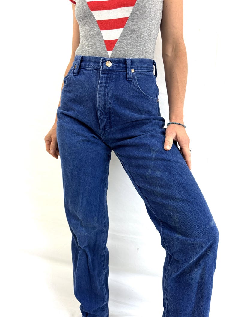K&ouml;nnte beinhalten: Eine Jeanshose mit hohem Bund in Blau mit geradem Bein. Die Jeans hat einen klassischen F&uuml;nftaschen-Stil und einen Knopfverschluss.