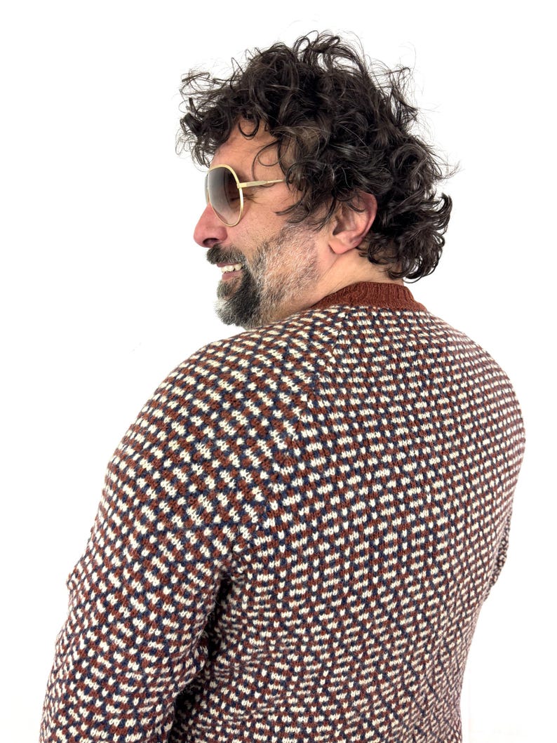 Puede incluir: Un su&eacute;ter estampado en marr&oacute;n, blanco y azul marino. El su&eacute;ter tiene cuello redondo y se usa con gafas de sol con montura dorada. La persona de la imagen tiene cabello oscuro rizado y barba.