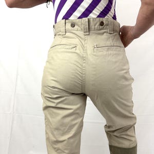 Puede incluir: Pantal&oacute;n beige de cintura alta con cierre de bot&oacute;n. El pantal&oacute;n tiene un bolsillo de parche en la parte posterior derecha y una costura en el centro de la espalda. El pantal&oacute;n est&aacute; doblado en la parte inferior y tiene un parche de tela marr&oacute;n en la parte inferior de las piernas.