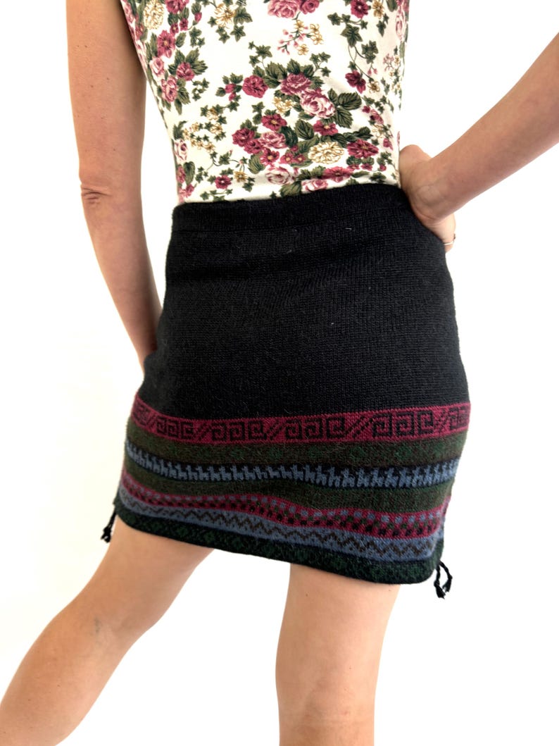 May include: Black knitted skirt with a colorful geometric pattern at the hem. The skirt has a drawstring at the side.