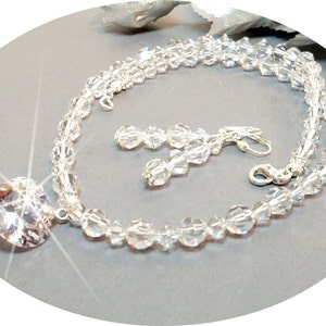 Puede incluir: Un conjunto de collar y pendientes de cristal con un gran colgante en forma de coraz&oacute;n. El collar est&aacute; hecho de cuentas de cristal transparente y los pendientes son de estilo colgante.
