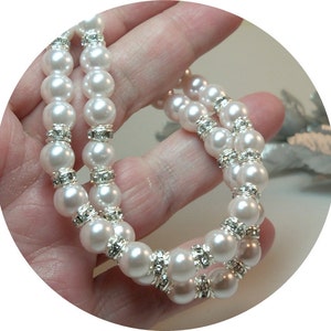 May include: A white pearl bracelet with silver rhinestone accents. The bracelet is made of faux pearls and is a double strand.