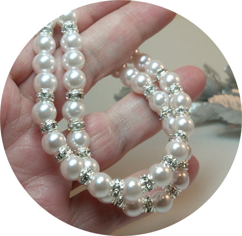 May include: A white pearl bracelet with silver rhinestone accents. The bracelet is made of faux pearls and is a double strand.