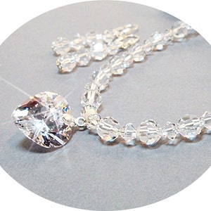 Puede incluir: Un collar de plata con un gran colgante de coraz&oacute;n de cristal y una cadena de cuentas de cristal.