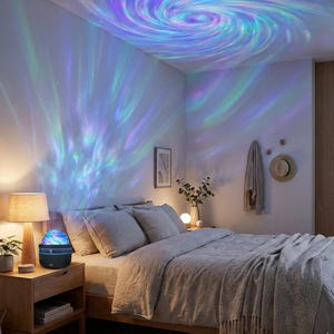 May include: A bedroom scene illuminated by a galaxy projector. The projector, on a wooden nightstand, casts swirling blue, green, and purple light patterns onto the ceiling and walls. A bed with gray bedding and pillows is in the foreground, with a lamp and decor.