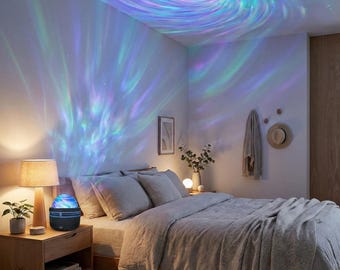 May include: A bedroom scene illuminated by a galaxy projector. The projector, on a wooden nightstand, casts swirling blue, green, and purple light patterns onto the ceiling and walls. A bed with gray bedding and pillows is in the foreground, with a lamp and decor.