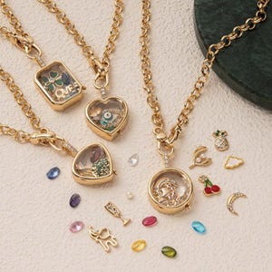 May include: Gold-toned charm necklaces with various pendant shapes, including a rectangle with the word "LOVE", a heart with an eye design, and a circle with a figure. Additional charms include a pineapple, cherry, and crescent moon.