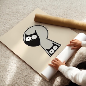 May include: A beige poster with a black cat illustration peeking through a keyhole shape. The text "SHHH... SOMEONE'S WATCHING!" is above the cat. A rolled-up poster is next to the main poster.