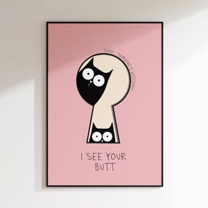 May include: A framed pink poster with a black border. The poster features a cartoon cat peeking through a keyhole, with the text "SHHH SOMEONE'S WATCHING!" and "I SEE YOUR BUTT".