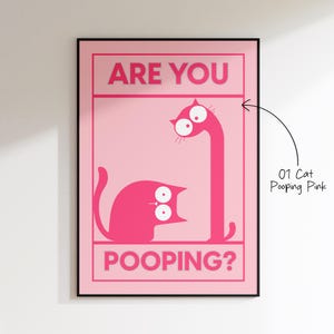 May include: Pink framed art print featuring two cartoon cats with large eyes. The text "ARE YOU POOPING?" is displayed in pink block letters. The art is titled "01 Cat Pooping Pink".