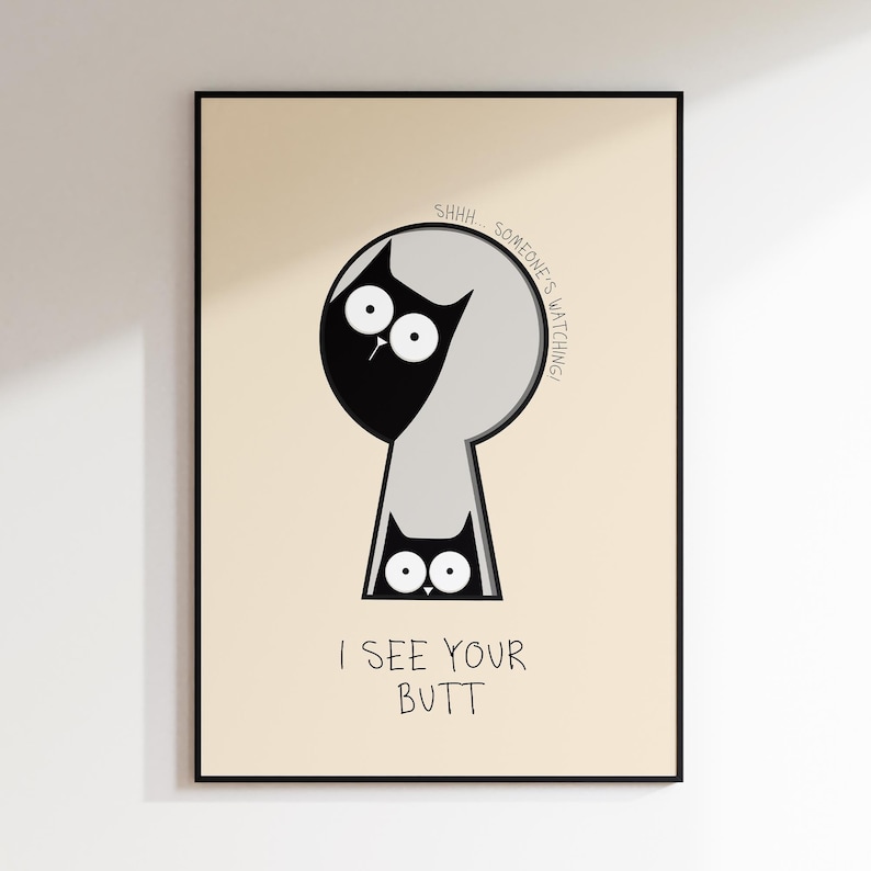 May include: A framed art print featuring a whimsical cat design. The artwork depicts a black cat peeking through a keyhole, with the text "SHHH... SOMEONE'S WATCHING!" and "I SEE YOUR BUTT" below. The background is a light beige.