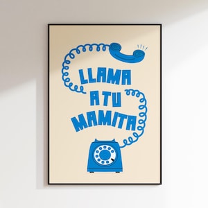 Puede incluir: Un póster enmarcado con fondo crema presenta un diseño de teléfono retro azul. El cable del teléfono forma las palabras "LLAMA A TU MAMITA" en azul, con el auricular en la parte superior y la base en la parte inferior. El póster está en un marco negro.