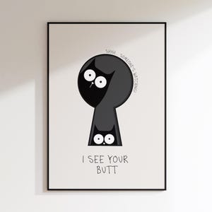 May include: A framed art print featuring a whimsical illustration of a black cat peeking through a keyhole. The text above reads "SHHH... SOMEONE'S WATCHING!" and below, "I SEE YOUR BUTT."