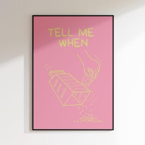 Puede incluir: Un póster rosa con el texto "TELL ME WHEN" en amarillo. Se muestra una mano rallando un bloque de queso sobre un rallador, con el queso rallado cayendo debajo.