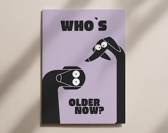 May include: A rectangular print with a light purple background features two black cartoon figures with white eyes. The text "WHO'S OLDER NOW?" is printed in bold black letters. The print is displayed on a light brown surface.