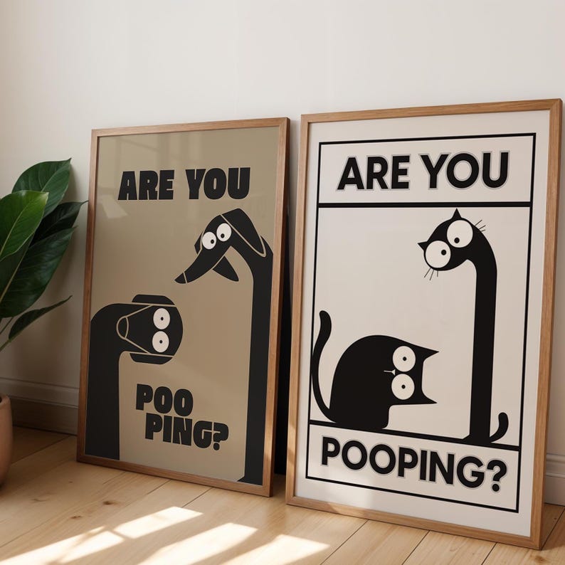 May include: Two framed art prints with humorous illustrations. One features a dog-like creature and the text "ARE YOU POO PING?" The other shows a cat-like creature with the text "ARE YOU POOPING?" Both prints have a minimalist design.