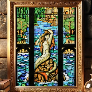Könnte beinhalten: Ein gerahmtes Buntglasfenster, das eine Meerjungfrau mit wallendem roten Haar zeigt, die auf einem Felsen sitzt, umgeben von blauem Wasser. Das Fenster ist in einem goldenen Rahmen gefasst und von einer Backsteinmauer umgeben.