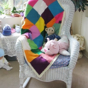 May include: A white wicker rocking chair with a colorful crocheted blanket, a pink stuffed animal, and a brown teddy bear.