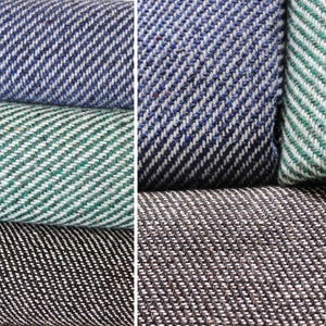 K&ouml;nnte beinhalten: Nahaufnahme von gefalteten Stoffmustern in Blau, Gr&uuml;n und Schwarz. Jeder Stoff hat ein diagonales Fischgr&auml;tmuster. Der blaue Stoff hat wei&szlig;e Akzente, der gr&uuml;ne hat wei&szlig;e Akzente und der schwarze hat wei&szlig;e Akzente.