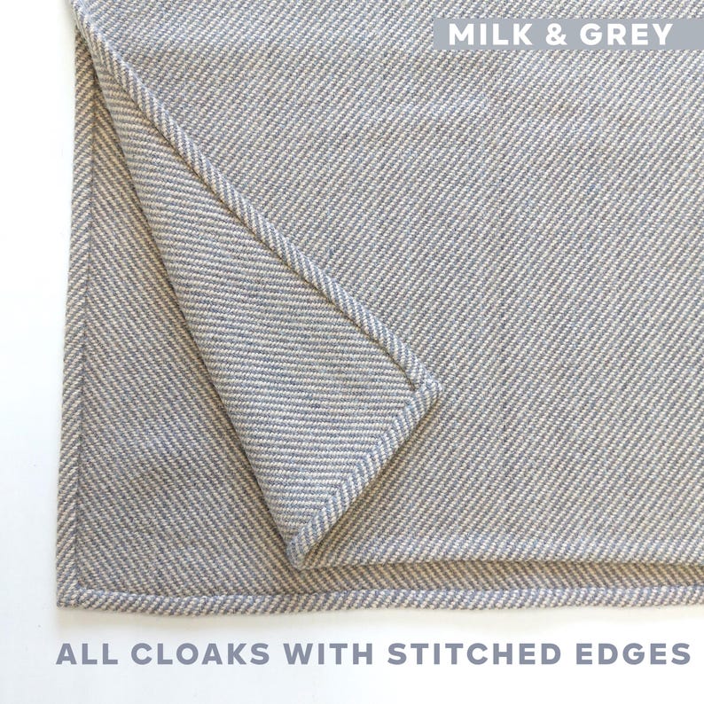 K&ouml;nnte beinhalten: Nahaufnahme eines gefalteten, hellgrauen Umhangs mit gen&auml;hten Kanten. Der Umhang hat ein Fischgr&auml;tenmuster. Der Text "MILK & GREY" steht oben. Der Text "ALL CLOAKS WITH STITCHED EDGES" steht unten.