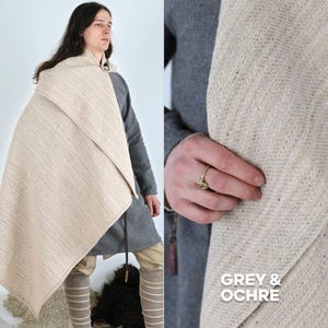 K&ouml;nnte beinhalten: Ein hellbeige gewebter Umhang, der &uuml;ber einer Person drapiert ist, kombiniert mit einer grauen Tunika und beigefarbenen Leggings. Der Umhang ist mit einer Metallschnalle befestigt. Das Bild zeigt auch den Text "GREY & OCHRE".