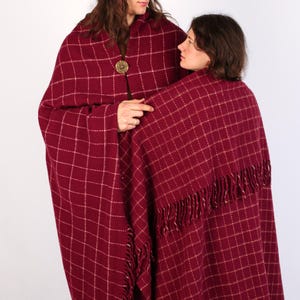 Pu&ograve; includere: Due persone indossano coperte a quadri rossi e bianchi con frange. La coperta &egrave; avvolta intorno alla persona a destra, mentre la persona a sinistra indossa la coperta come uno scialle.