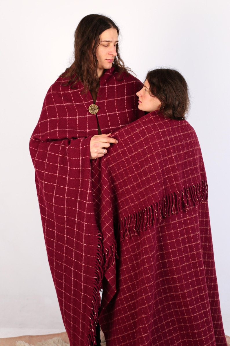 Pu&ograve; includere: Due persone indossano coperte a quadri rossi e bianchi con frange. La coperta &egrave; avvolta intorno alla persona a destra, mentre la persona a sinistra indossa la coperta come uno scialle.
