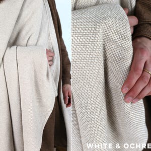 K&ouml;nnte beinhalten: Eine gewebte Decke in Wei&szlig;- und Ockert&ouml;nen. Die Decke hat ein strukturiertes Aussehen und ist drapiert. Der Text "WHITE & OCHRE" ist in der unteren rechten Ecke sichtbar.