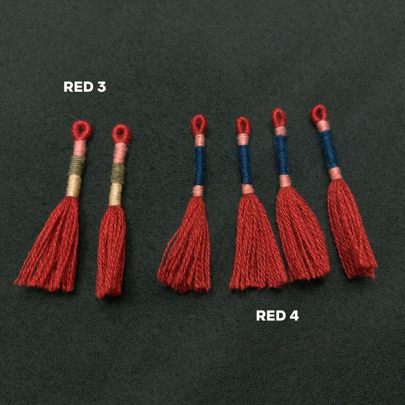 Pode incluir: Seis borlas vermelhas com detalhes azuis e brancos. As borlas est&atilde;o dispostas em fila, com o texto "RED 3" acima das tr&ecirc;s primeiras borlas e "RED 4" abaixo das tr&ecirc;s &uacute;ltimas borlas.