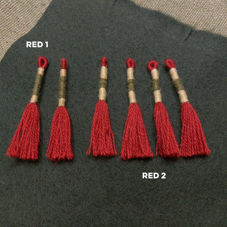 Pode incluir: Sete borlas vermelhas com detalhes verdes e bege. As borlas est&atilde;o dispostas em duas filas, etiquetadas como "RED 1" e "RED 2".