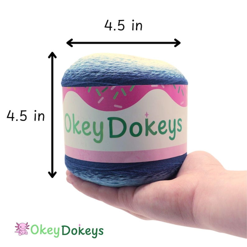 May include: A cylindrical ball of yarn, 4.5 inches in height and width, held in a hand. The yarn is a gradient of blue and yellow. The label reads "Okey Dokeys" with a pink and white design.