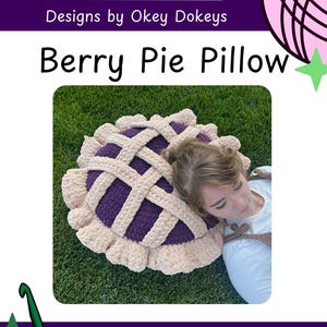 Puede incluir: Una almohada hecha a mano con forma de tarta de bayas. Presenta un relleno morado, una corteza de rejilla beige y un borde con volantes. El texto "Berry Pie Pillow" está visible.