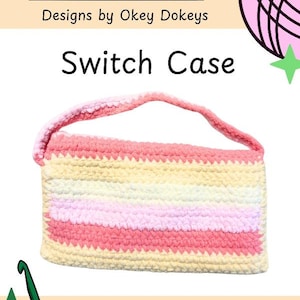 Può includere: Una custodia rettangolare all'uncinetto con manico, caratterizzata da strisce orizzontali nei toni del crema, rosa chiaro e rosa scuro. Il testo Okey Dokeys Designs by Okey Dokeys Switch Case è visibile in alto, con un'icona di axolotl e un gomitolo.