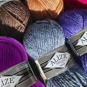May include: Close-up of six balls of yarn in various colours, including brown, orange, purple, blue, and pink. The yarn is labelled "Alize Superlana Maxi" and features the text "Yünlü karışımları tercih ediniz." which translates to "Choose wool blends."