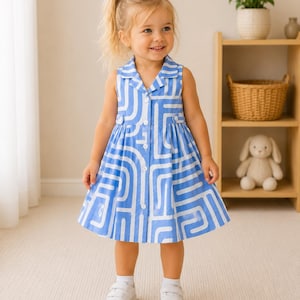 May include: A sleeveless dress featuring a blue and white geometric maze pattern, a collared neckline, and a front button-down closure. The dress has a fitted bodice with two small decorative tabs at the waist and a flared skirt that reaches the knees.