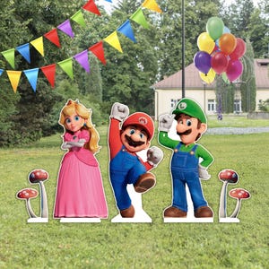 Pode incluir: Um conjunto de recortes de cartão com a Princesa Peach num vestido cor-de-rosa, o Mario com uma camisa vermelha e jardineiras azuis, e o Luigi com uma camisa verde e jardineiras azuis, acompanhados por quatro cogumelos, bandeirolas e balões.