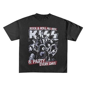 May include: Black t-shirt featuring a graphic of the rock band KISS. The design includes the band's logo and the text "ROCK & ROLL ALL NITE" and "& PARTY EVERY DAY!" in a distressed style. The image shows the band members performing.