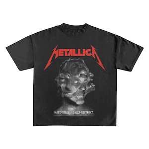May include: Black t-shirt featuring the band name "Metallica" in red, above a distorted face graphic. The text "HARDWIRED...TO SELF-DESTRUCT" is printed below the graphic. The shirt is a classic crew neck style.
