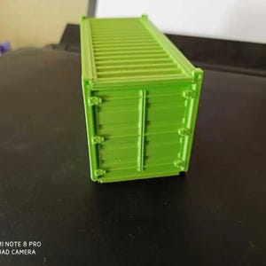 May include: A bright green model of a shipping container. The container is made of plastic and has a detailed design.
