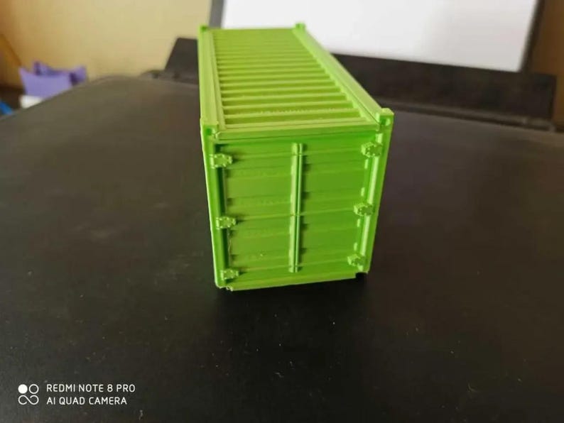 May include: A bright green model of a shipping container. The container is made of plastic and has a detailed design.