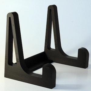 May include: A black, wooden display stand with two angled supports. The stand is designed to hold a plate or other flat object.